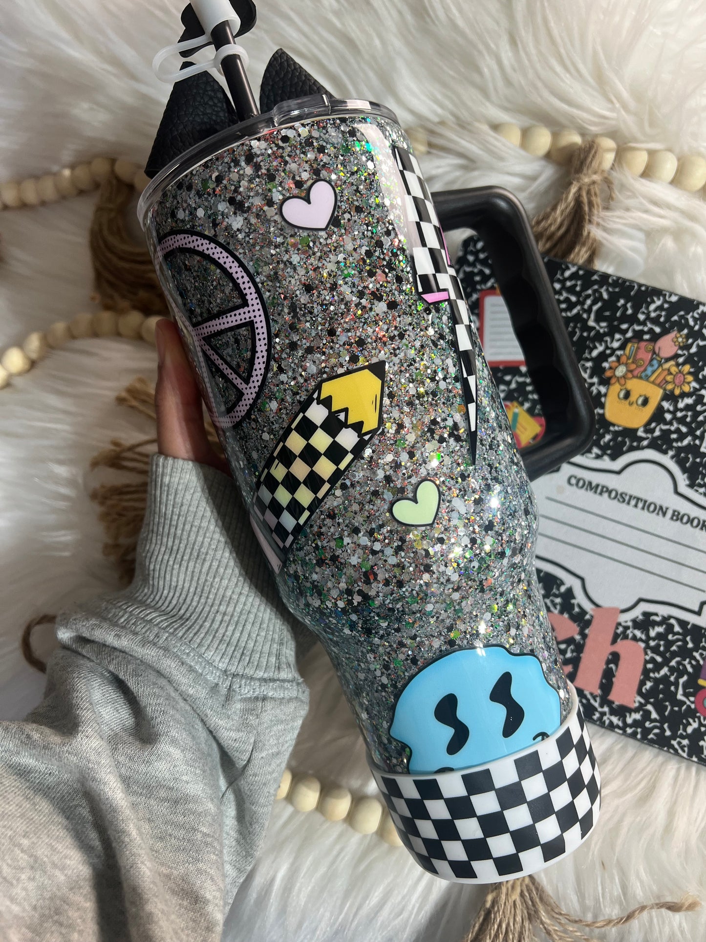 Composition notebook themes tumbler, 40oz with retro school supply decals. Tumbler has a handle and is displayed on a soft surface.