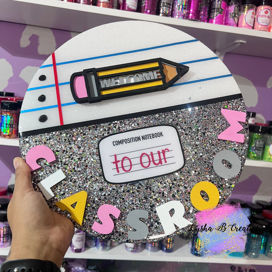 Decorative sign with 'Welcome to our Classroom' text, held by a hand in a store setting.